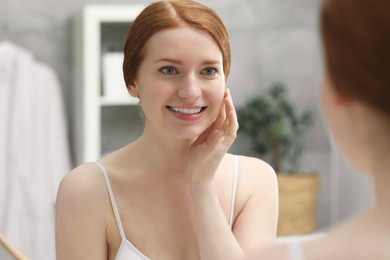Photo of Smiling woman with freckles near mirror in bathroom