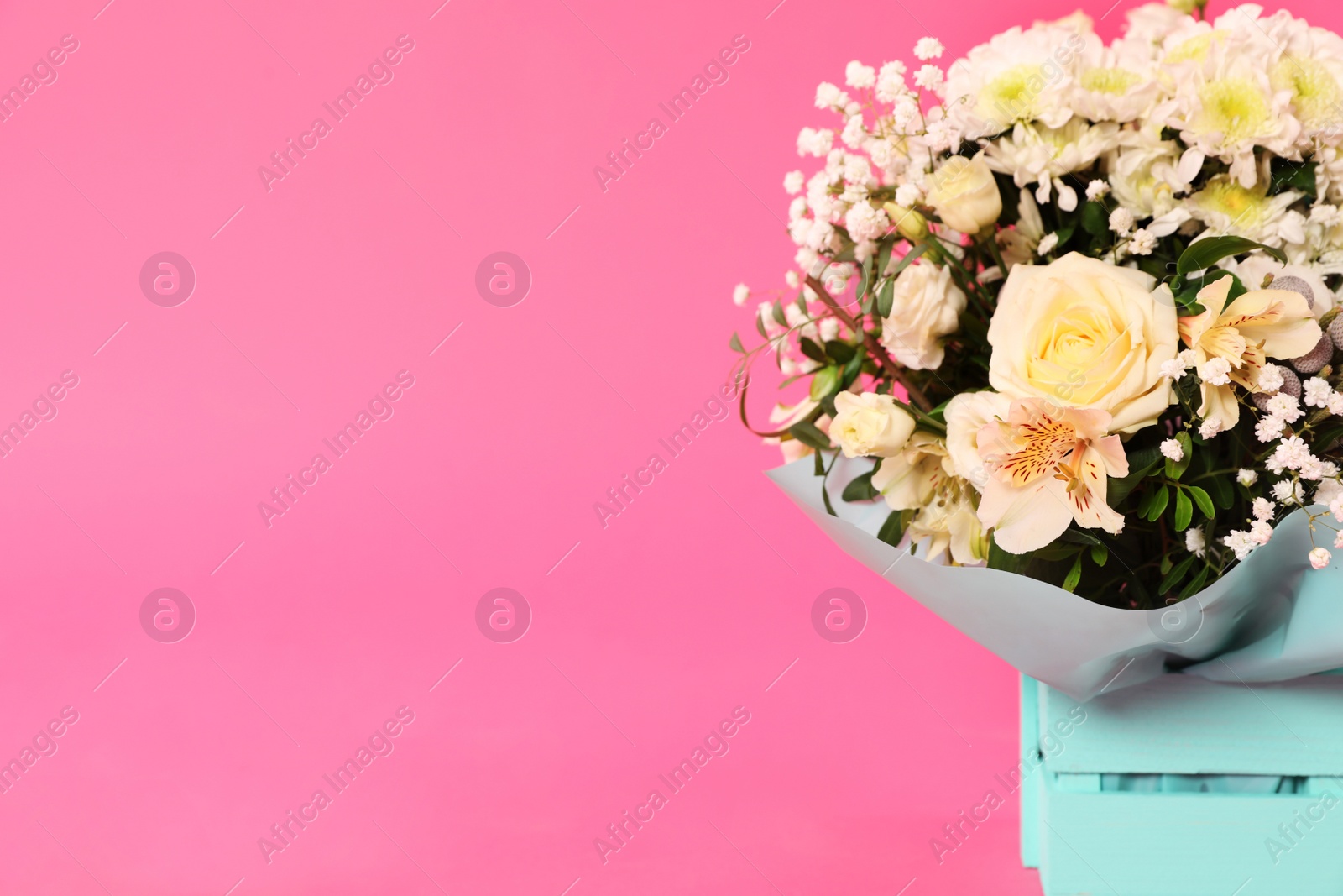 Photo of Beautiful bouquet of flowers in decorative crate on color background. Space for text