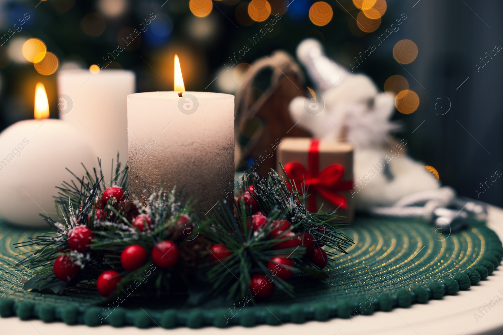 Photo of Beautiful burning candles and Christmas decor on white table against festive lights. Space for text