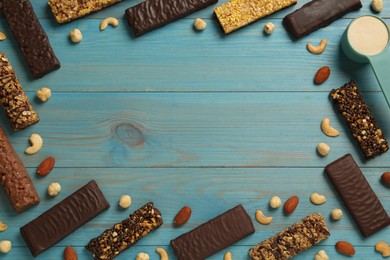 Photo of Frame of different tasty bars, nuts and protein powder on light blue wooden table, flat lay. Space for text