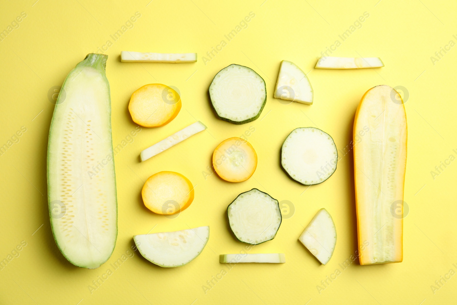 Photo of Fresh ripe cut zucchinis on yellow background, flat lay