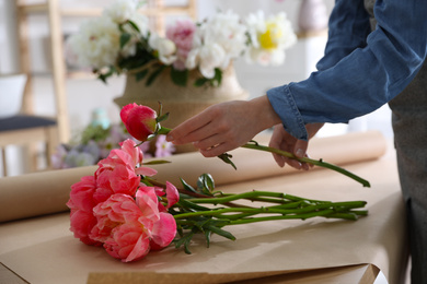 Florist making beautiful peony bouquet at table, closeup