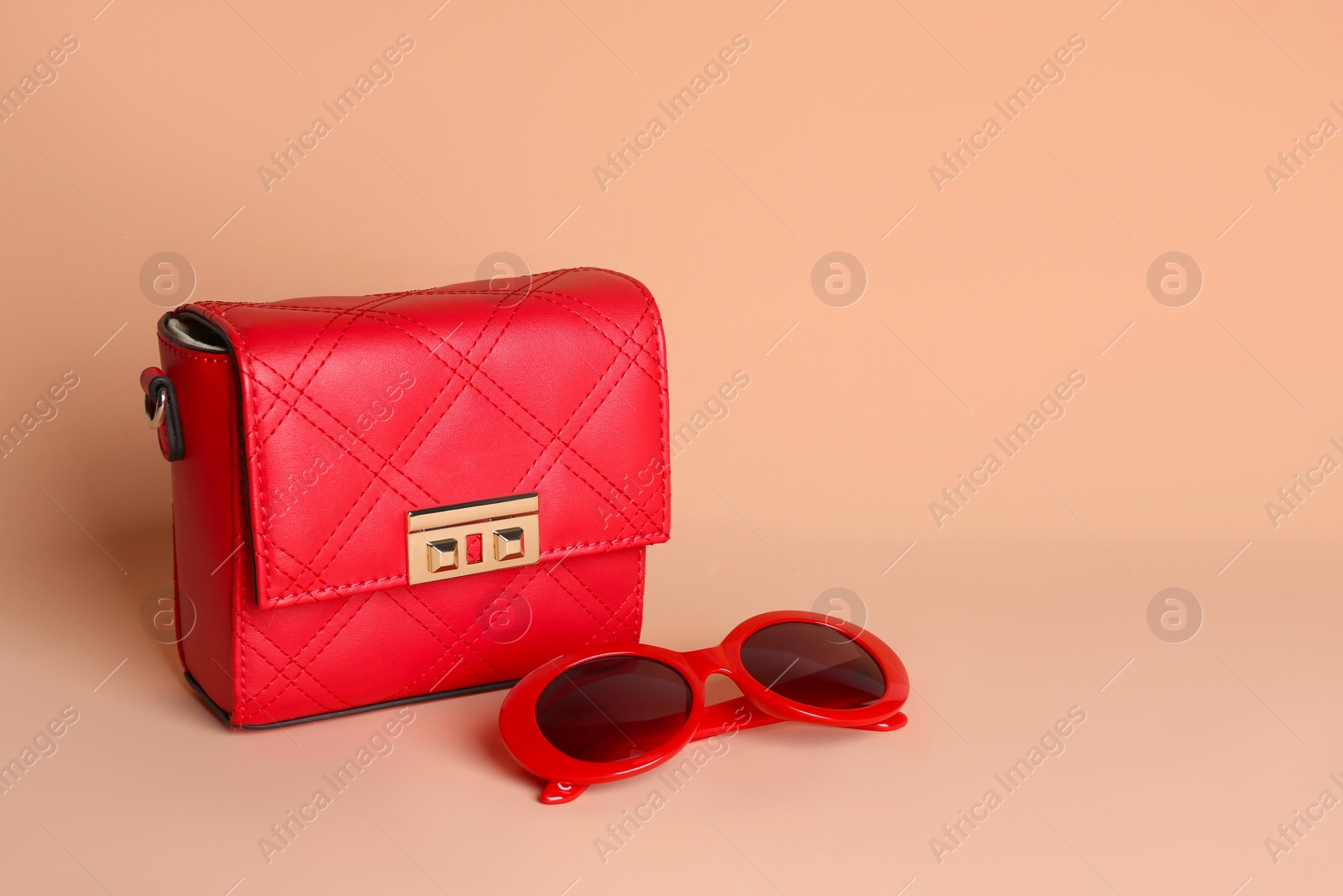 Photo of Stylish woman's bag and sunglasses on pale pink background. Space for text