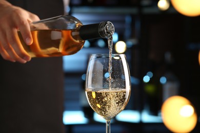 Photo of Bartender pouring white wine into glass indoors, closeup