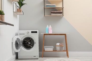 Photo of Modern washing machine in laundry room interior