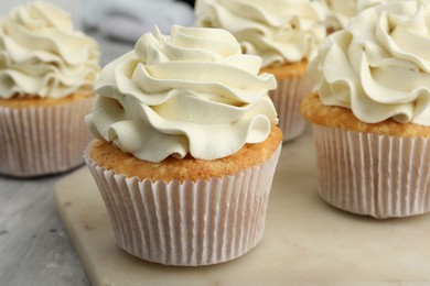 Photo of Tasty cupcakes with vanilla cream on grey table, closeup