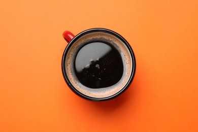 Fresh coffee in cup on orange background, top view