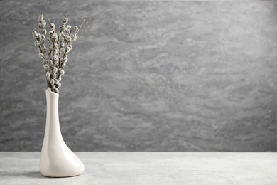 Photo of Beautiful pussy willow branches in vase on light grey table, space for text