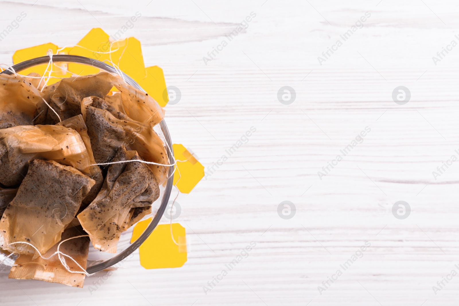 Photo of Bowl with used tea bags on white wooden table, top view. Space for text