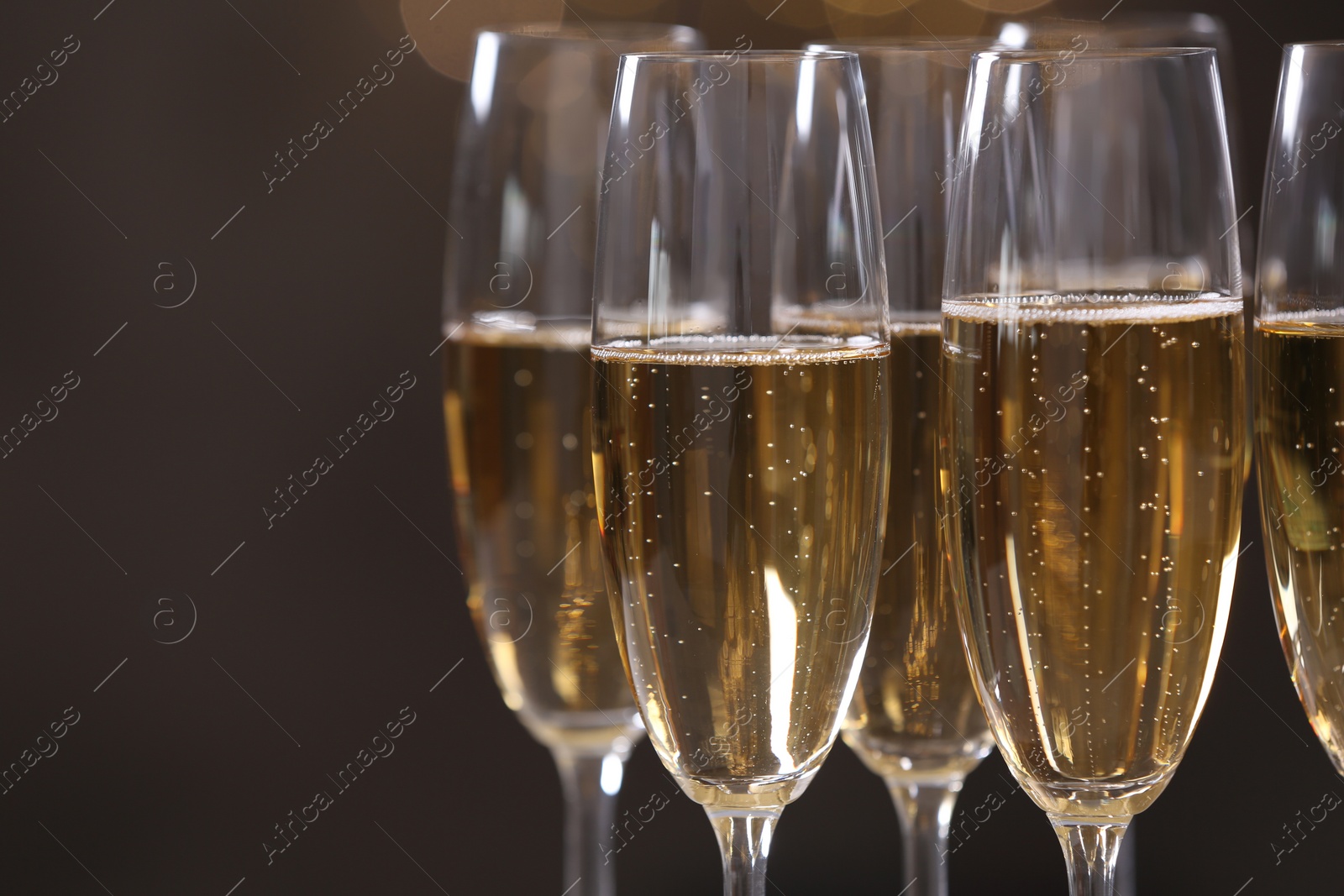 Photo of Glasses of champagne on dark background, closeup. Space for text