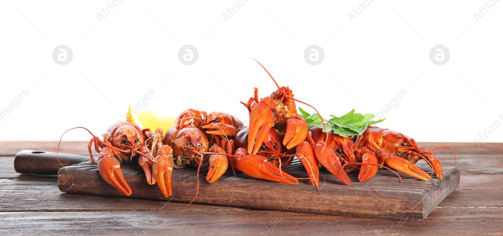 Photo of Delicious boiled crayfishes on wooden table against white background