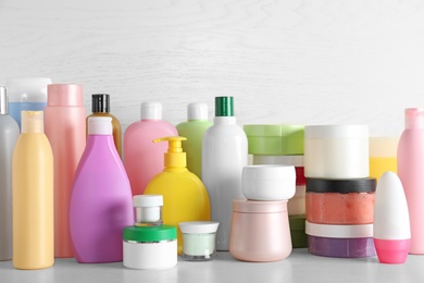 Photo of Different body care products on table against light wooden background