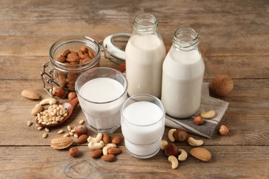 Photo of Different nut milks in glassware on wooden table