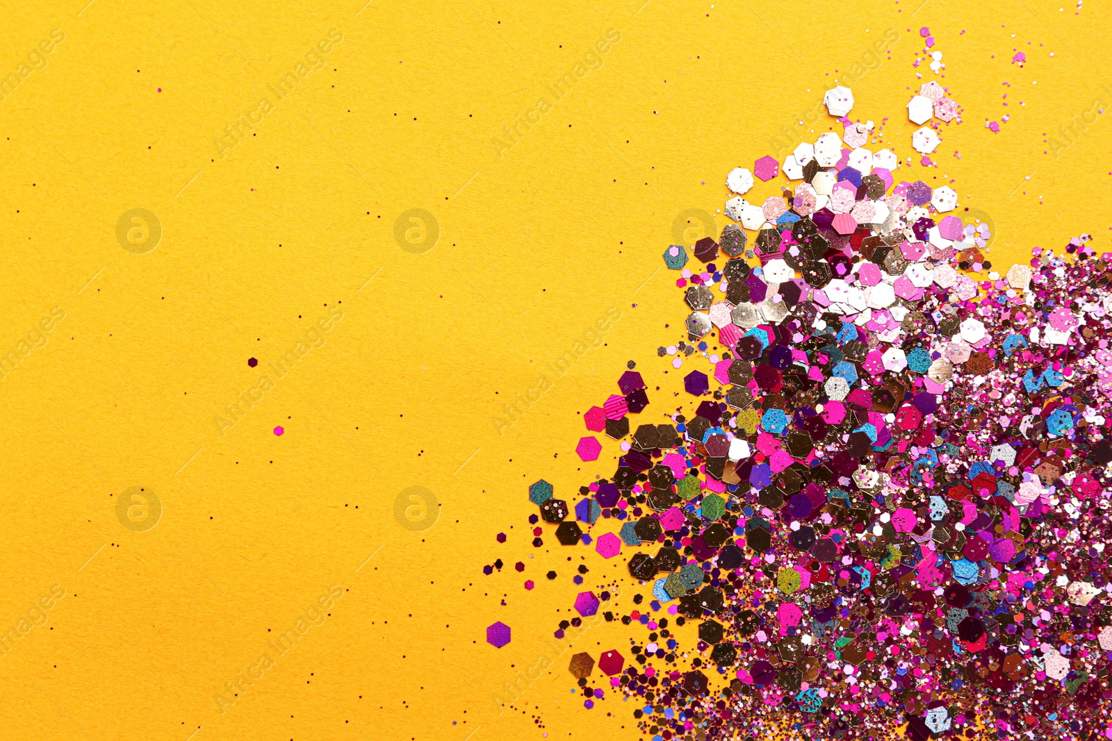 Photo of Shiny bright glitter on yellow background, flat lay. Space for text