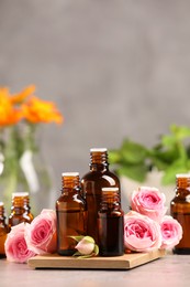 Photo of Bottles with essential oil and roses on light table. Space for text
