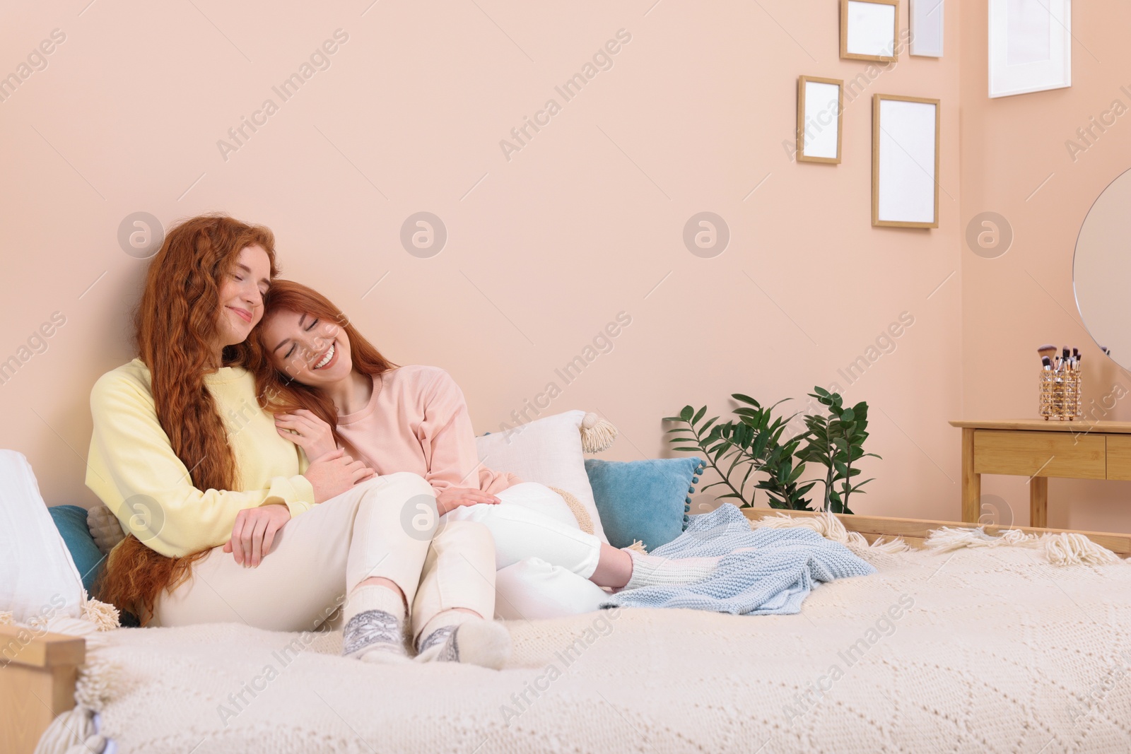 Photo of Portrait of beautiful young redhead sisters in bedroom. Space for text