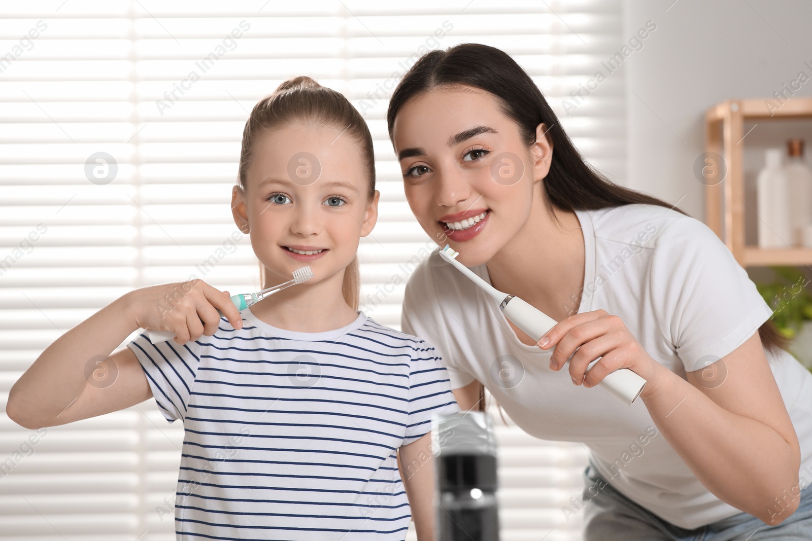 Photo of Mother and her daughter brushing teeth together in bathroom