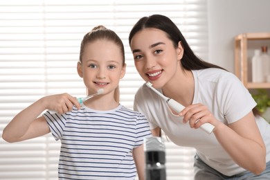 Mother and her daughter brushing teeth together in bathroom