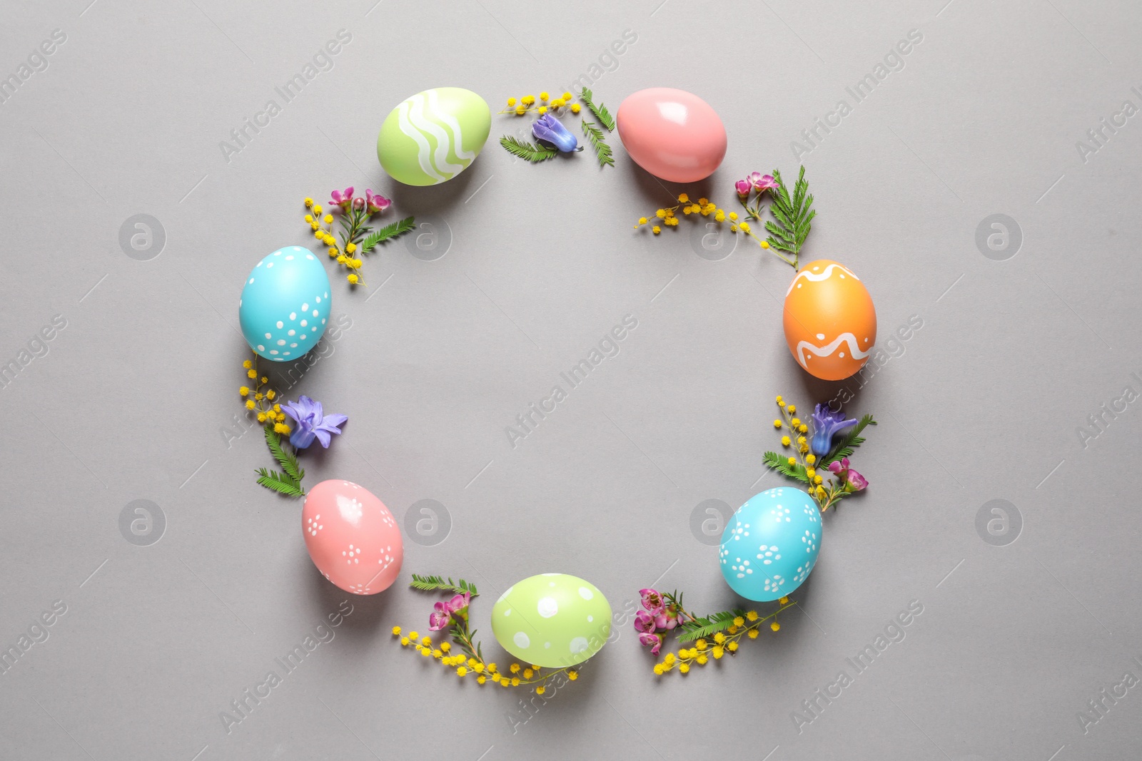 Photo of Flat lay composition of painted Easter eggs and flowers on color background, space for text