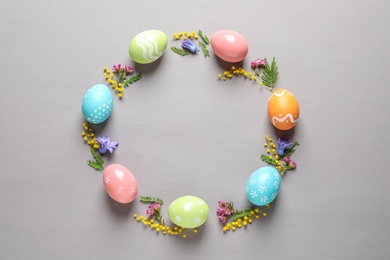 Photo of Flat lay composition of painted Easter eggs and flowers on color background, space for text