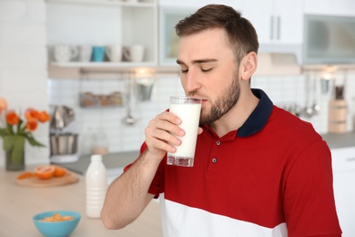 Photo of Young man drinking tasty milk at home