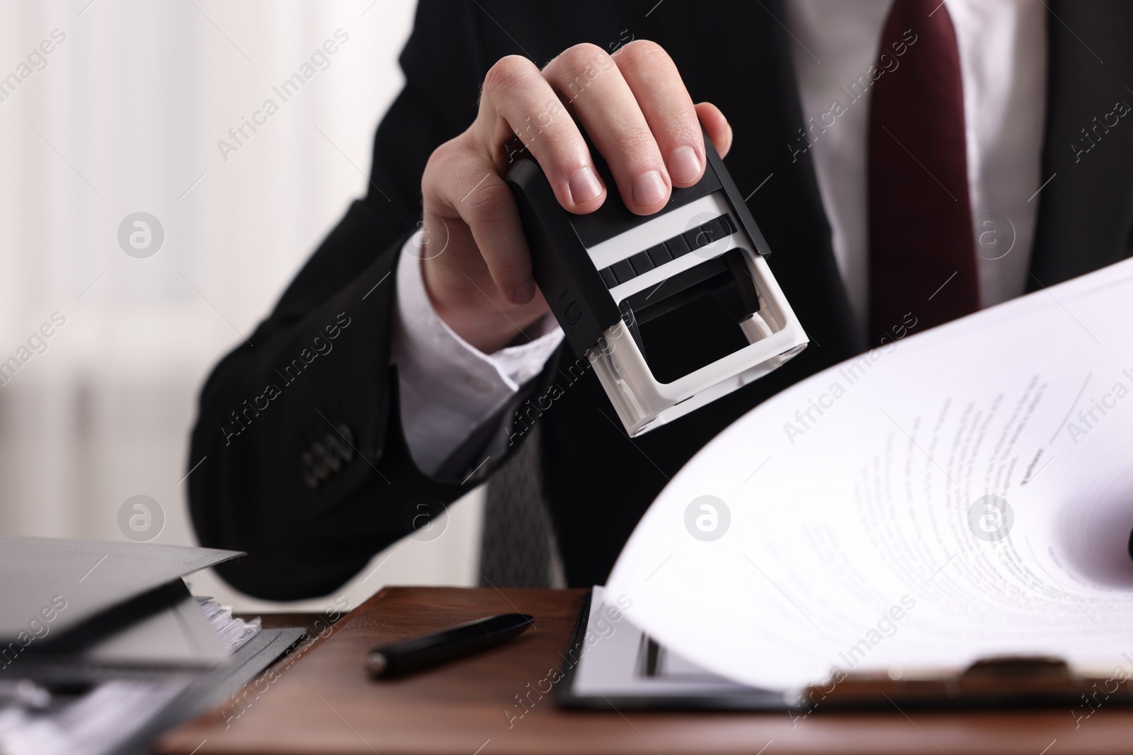 Photo of Notary stamping document at table in office, closeup