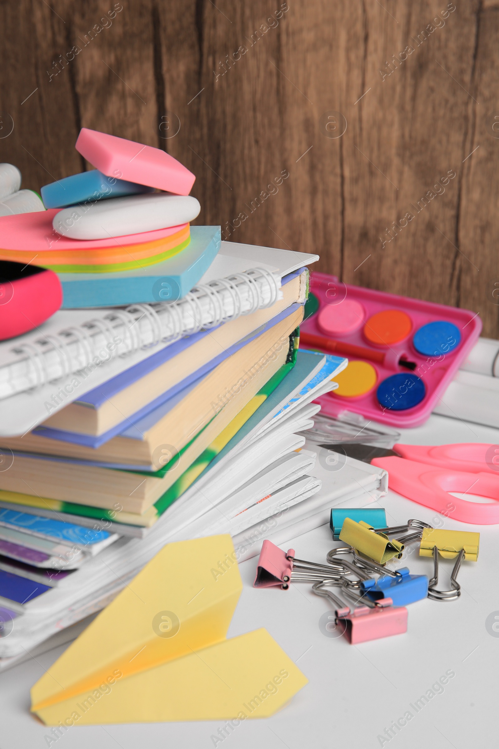 Photo of Many different books, paper plane and school stationery on white table. Back to school