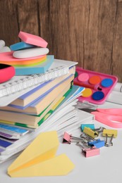 Photo of Many different books, paper plane and school stationery on white table. Back to school