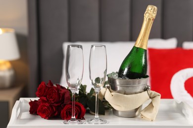 Honeymoon. Sparkling wine, glasses and bouquet of roses on table in room