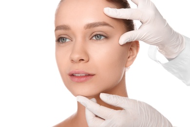 Photo of Doctor examining young woman face before cosmetic surgery on white background