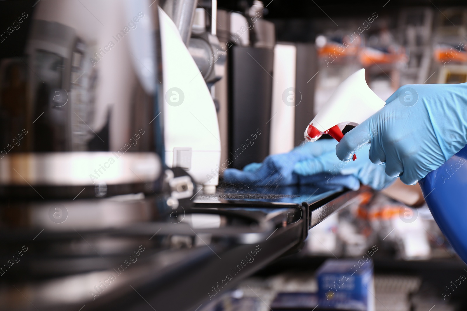 Photo of Woman cleaning shelf with rag and detergent in electronic store, closeup