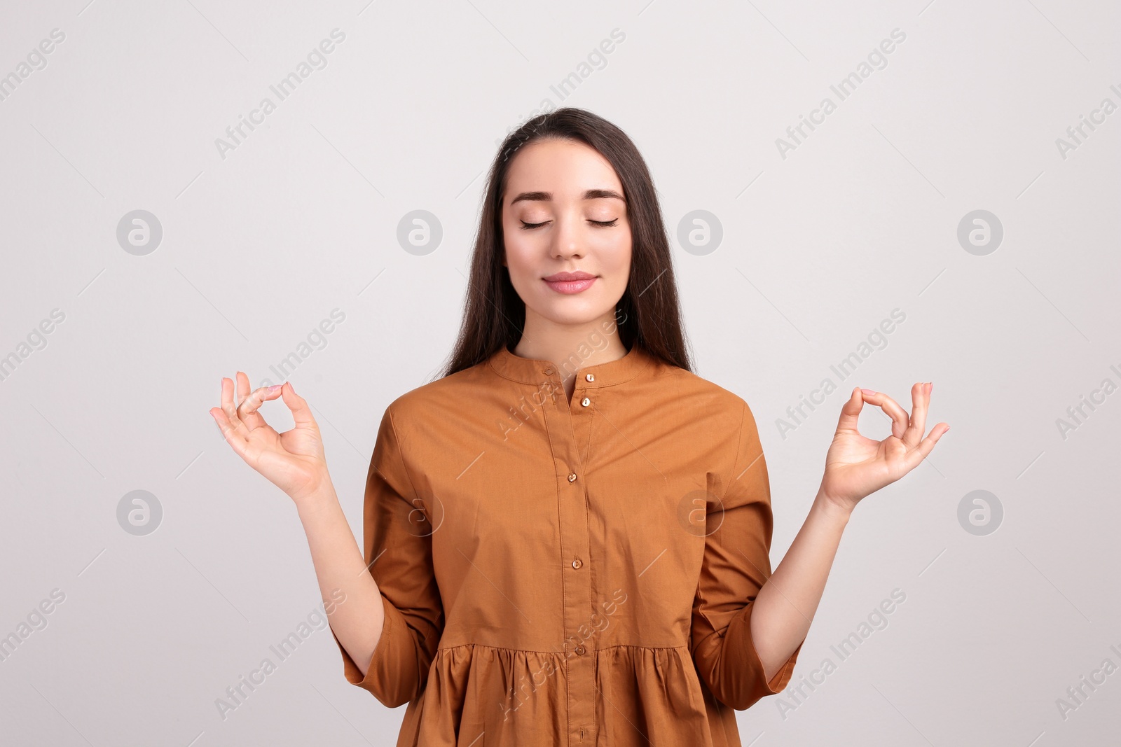 Photo of Young woman meditating on beige background. Stress relief exercise