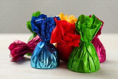 Photo of Candies in colorful wrappers on white wooden table, closeup