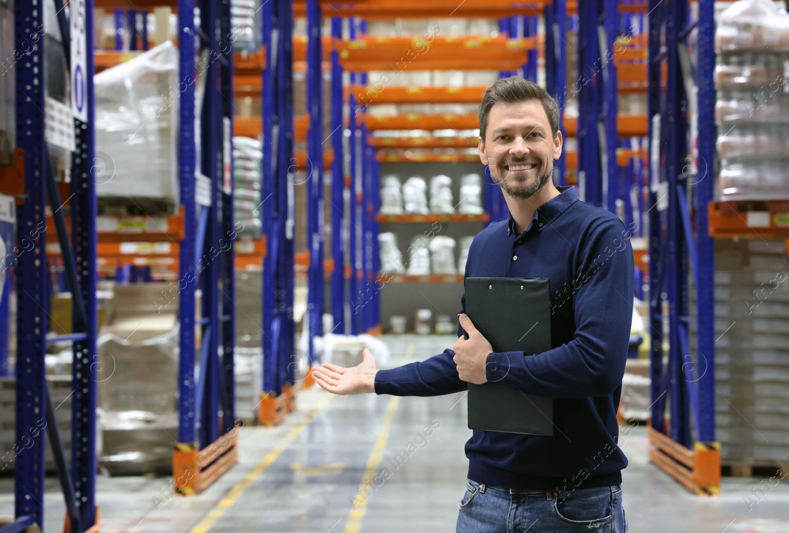 Photo of Happy manager holding clipboard in warehouse with lots of products. Space for text