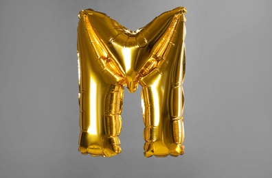 Photo of Golden letter M balloon on grey background