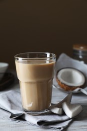 Photo of Glass of coffee with coconut milk and nut pieces on white wooden table
