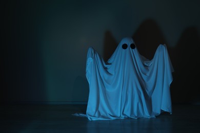 Photo of Creepy ghost. Woman covered with sheet in color light, space for text