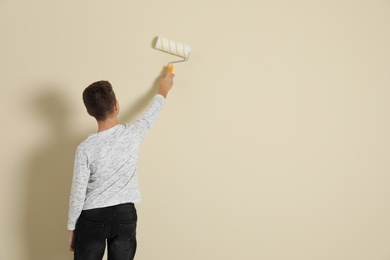 Child painting color wall with roller brush. Space for text