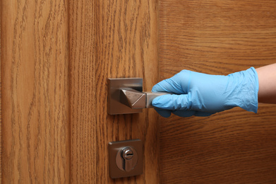 Photo of Woman in protective gloves opening wooden door, closeup