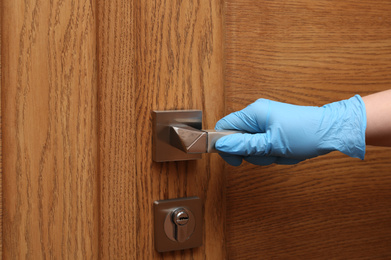 Woman in protective gloves opening wooden door, closeup