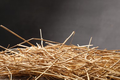 Photo of Pile of dried straw on table against dark background, closeup