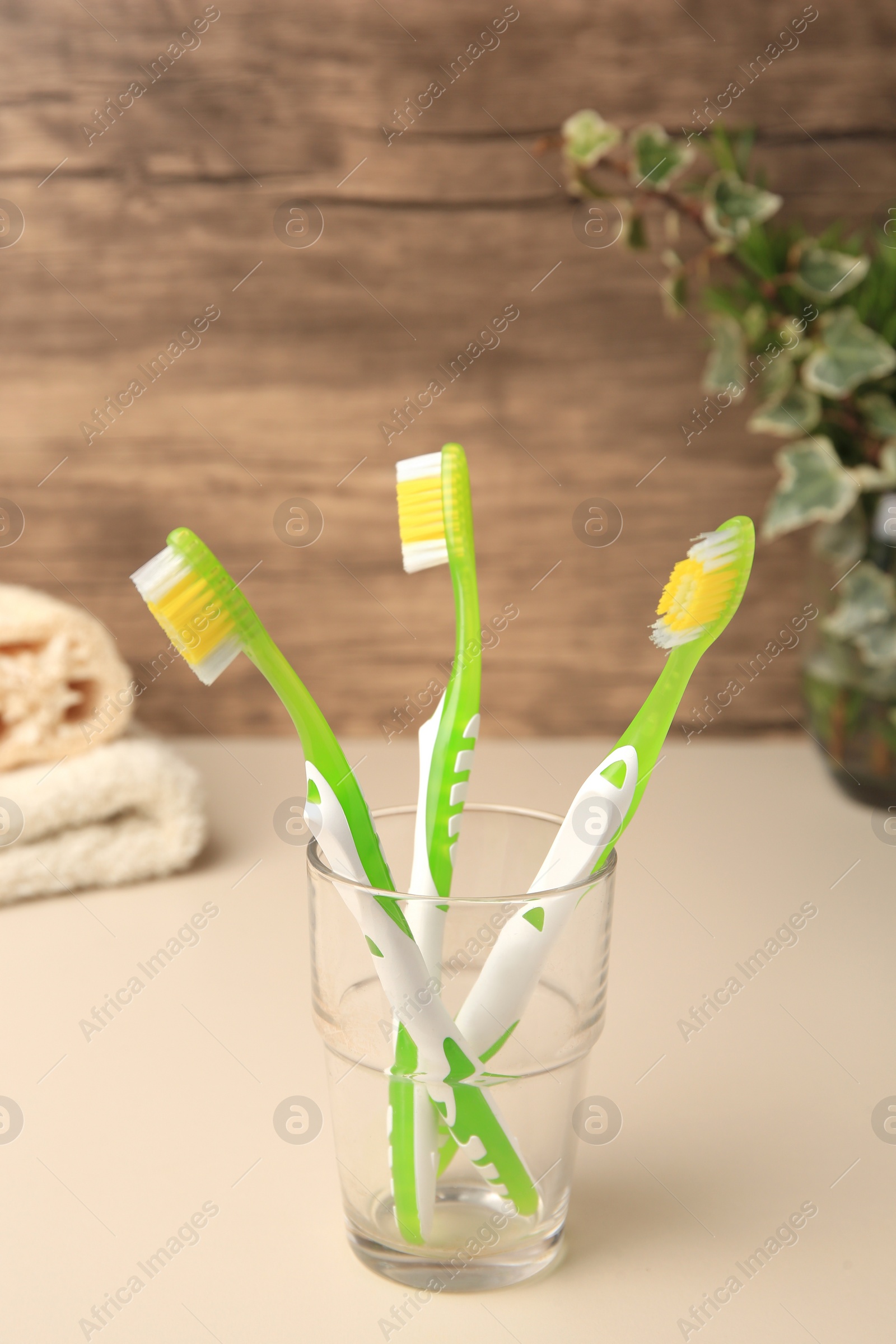 Photo of Toothbrushes in glass holder on beige table