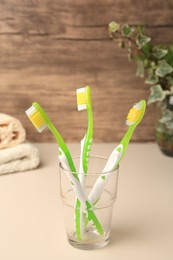 Photo of Toothbrushes in glass holder on beige table
