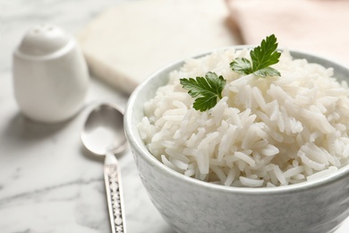 Photo of Bowl of tasty cooked rice with parsley served on table, closeup. Space for text