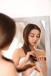 Woman with damaged hair in front of mirror indoors