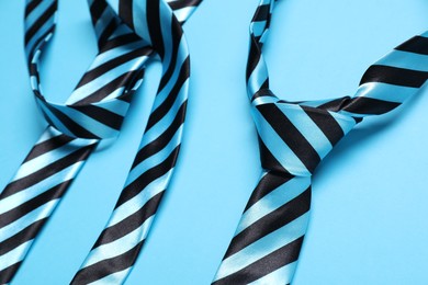 Photo of Striped neckties on light blue background, closeup