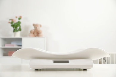 Photo of Modern digital baby scales on table in room. Space for text