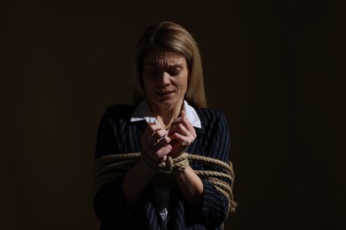 Woman tied up and taken hostage on dark background