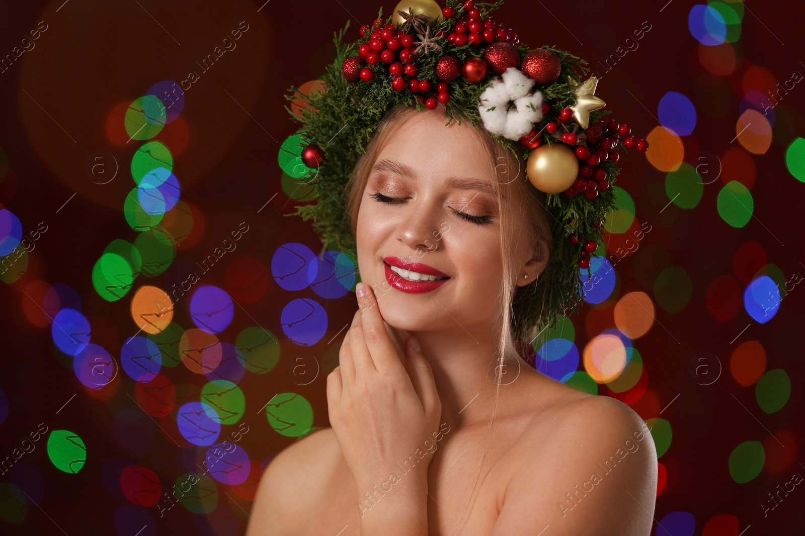 Photo of Beautiful young woman wearing Christmas wreath on blurred background. Bokeh effect