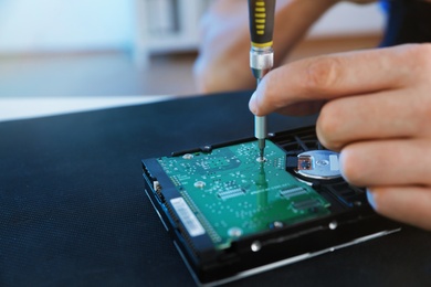 Photo of Male technician repairing hard drive at table, closeup. Space for text